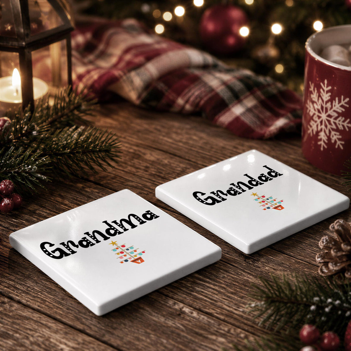 two white coasters with the text "Grandma" printed on them, placed on a wooden surface. There are also Christmas decorations, such as pine cones and a lit candle, in the background, creating a festive atmosphere.