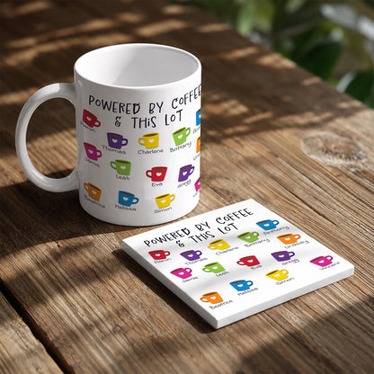 A white coffee mug with colorful coffee cups printed on it, placed on a wooden table next to a coaster with a list of coffee names printed on it.