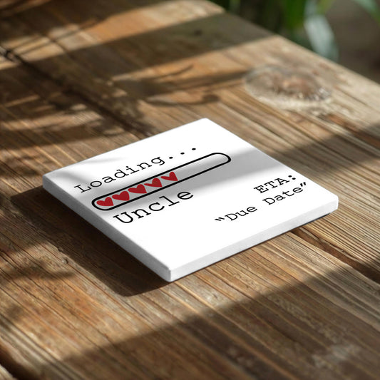 A white square coaster with a loading progress bar and the text "Uncle" and "Due Date" printed on it, placed on a wooden surface.