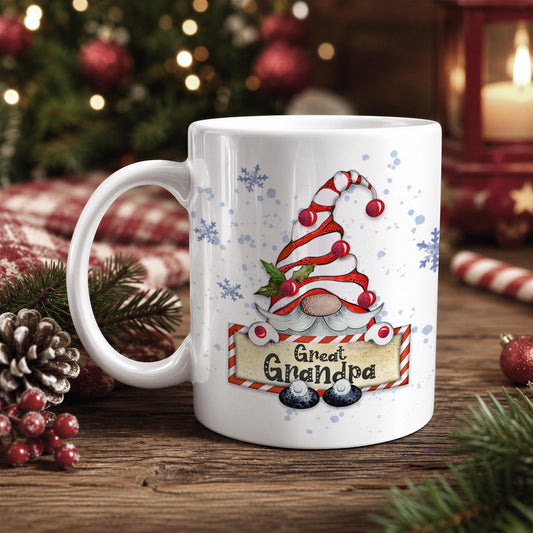 A white mug with a Christmas-themed design featuring a gnome wearing a red and white striped hat and the text "Great Grandpa" on it, placed on a wooden surface with Christmas decorations in the background.