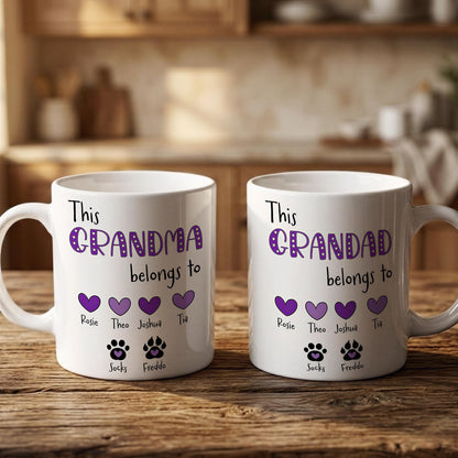 Two white mugs with purple text and paw prints, placed on a wooden surface.