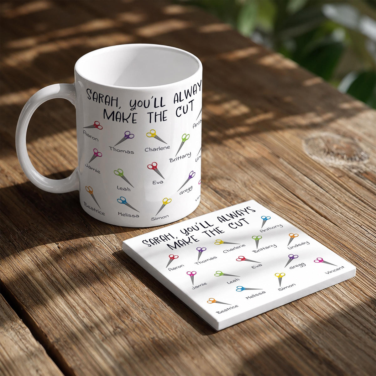 A white mug with a humorous message printed on it, and a small white note card with a list of names printed on it, both placed on a wooden surface.