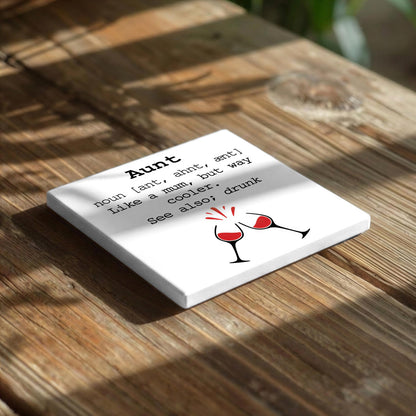 A white square coaster with black text and a graphic of two wine glasses on a wooden surface.
