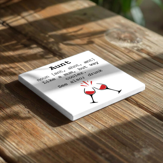 A white square coaster with black text and a graphic of two wine glasses on a wooden surface.