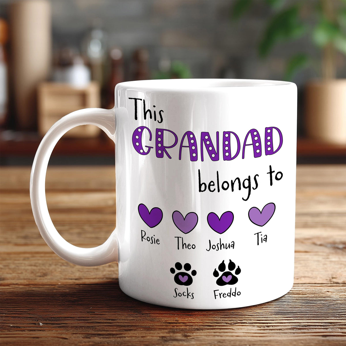 A white mug with a personalized message that reads "This GRANDDAD belongs to Rosie, Theo, Joshua, Tia, Socks, Freddo" along with paw prints.